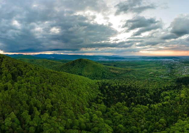 Aerial view of dark mountain hills covered with green mixed pine and lush forest in evening