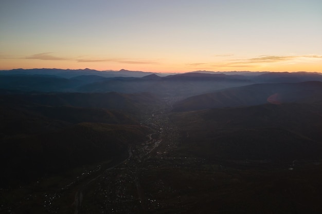 Vista aerea di scure colline di montagna al tramonto cime nebbiose e valli nebbiose in serata