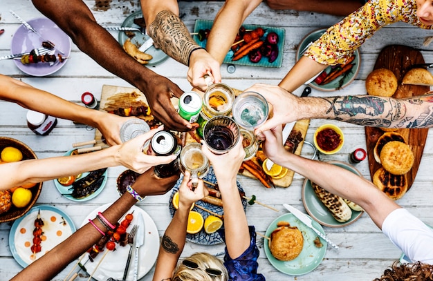 Aerial view of diverse hands clinking beverage together