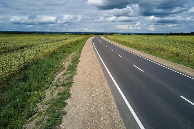 Aerial view of empty intercity road between green agricultural fields Top view from drone of highway roadway