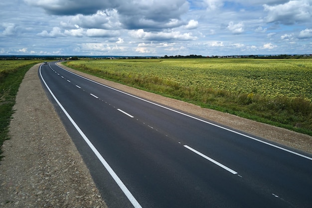 Aerial view of empty intercity road between green agricultural fields Top view from drone of highway roadway