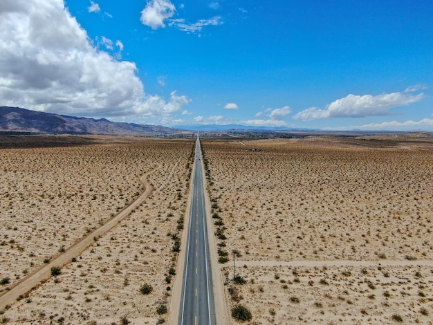 ジョシュアツリーパークUSAの次の無限の砂漠のまっすぐな道路の航空写真長いまっすぐな舗装道路