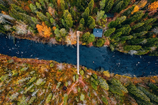 Aerial view of fall forest and blue river with bridge in Finland Beautiful autumn landscape