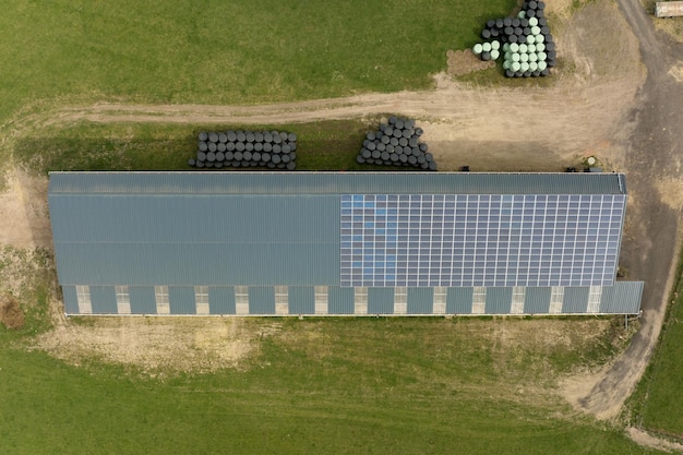 Aerial view of farm building with photovoltaic solar panels mounted on rooftop for producing clean ecological electricity Production of renewable energy concept