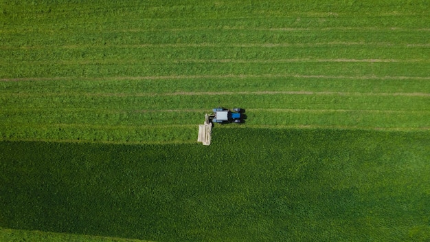 Aerial view of farming tractor mowing green field