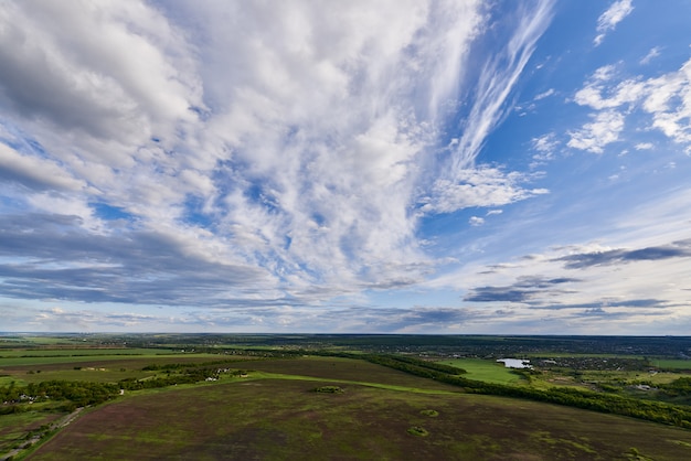 Aerial view of farmland under a blue sky with clouds.