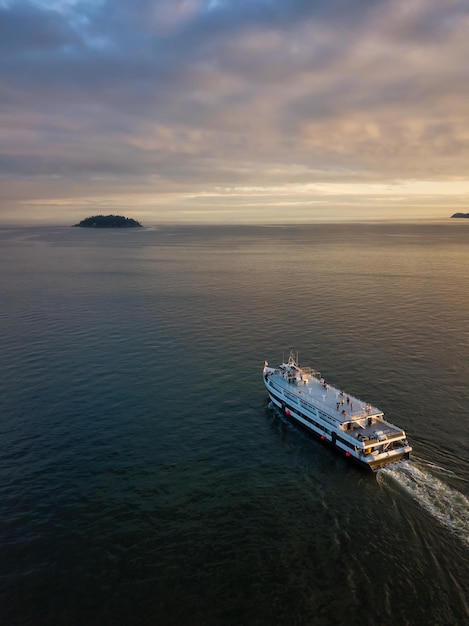 Aerial view of a ferry boat in the ocean during a vibrant cloudy sunset
