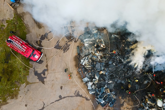 Aerial view of firefighters extinguishing fire in industrial area.