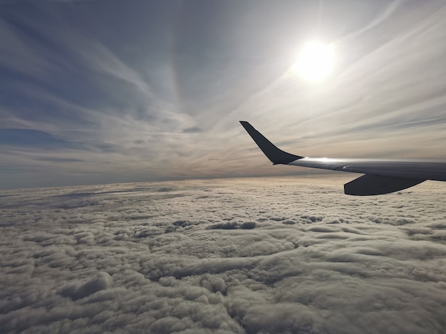 Aerial view of fluffy clouds with the sun under the wing of the plane