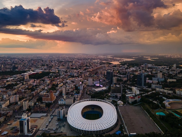 Aerial view of the football stadium in the city against the backdrop of sunset and beautiful clouds