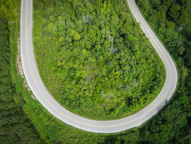 山の緑の木々のトップビュー道路曲線上の道路上の車で空撮森の自然