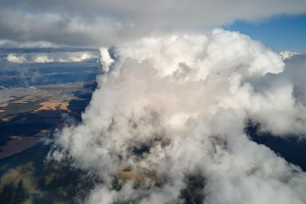 Фото Аэропортный вид из окна самолета на большой высоте земли, покрытой пухлыми кумулусными облаками, образующимися перед дождливым штормом