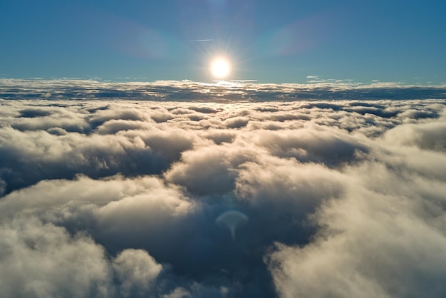 Aerial view from airplane window at high altitude of dense puffy cumulus clouds flying in evening