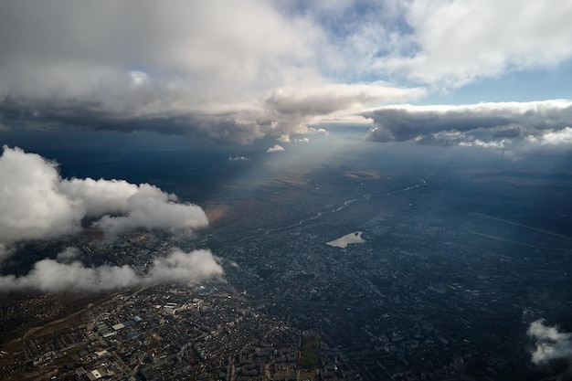 흰색 푹신한 적운 구름으로 덮인 먼 도시의 높은 고도에서 비행기 창에서 공중보기