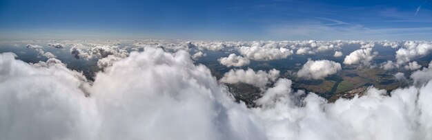 Aerial view from airplane window at high altitude of earth covered with puffy cumulus clouds forming before rainstorm.