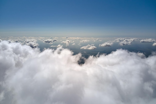폭풍우가 오기 전에 형성되는 푹신한 적운 구름으로 덮인 지구의 높은 고도에 있는 비행기 창에서 공중 전망.