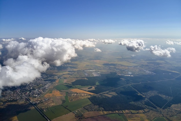 Vista aerea dal finestrino dell'aeroplano ad alta quota della terra coperta da nubi cumuliformi gonfie che si formano prima del temporale