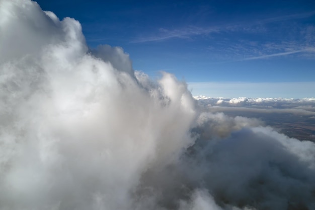 Aerial view from airplane window at high altitude of earth covered with puffy cumulus clouds forming before rainstorm