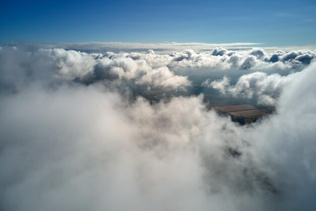 Photo aerial view from airplane window at high altitude of earth covered with puffy cumulus clouds forming before rainstorm