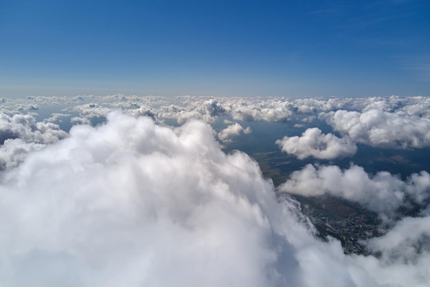 Aerial view from airplane window at high altitude of earth\
covered with white puffy cumulus clouds.