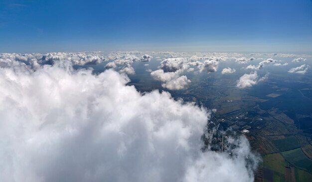 Aerial view from airplane window at high altitude of earth covered with white puffy cumulus clouds