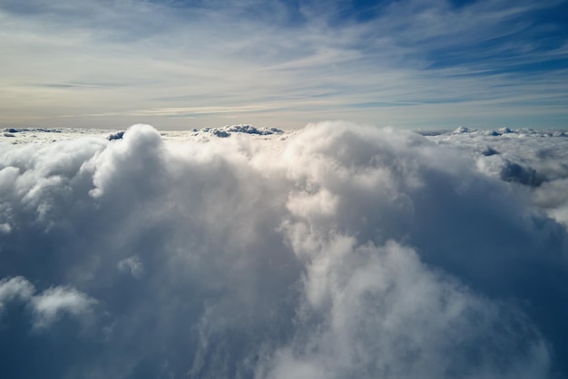 Aerial view from airplane window at high altitude of earth covered with white puffy cumulus clouds