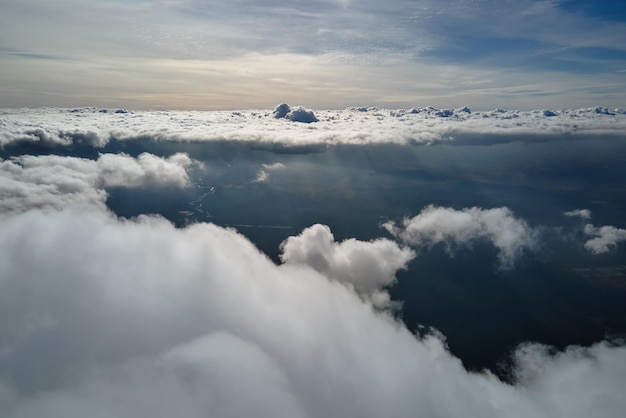 白いふくらんでいる積雲で覆われた地球の高高度での飛行機の窓からの空中写真