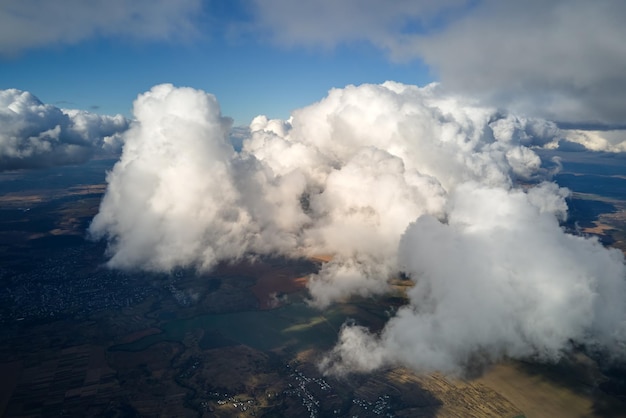 白い膨らんだクムルス雲で覆われた地球の高空の飛行機の窓からの空中景色