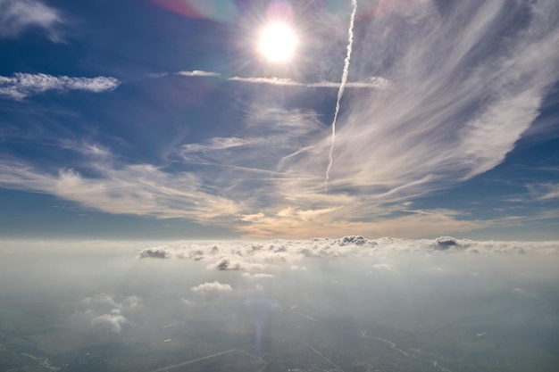 Вид с воздуха из окна самолета на большой высоте земли, покрытой белым тонким слоем туманной дымки и далеких облаков