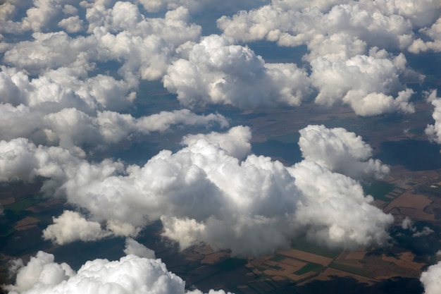 明るい晴れた日の白いふくらんでいる雲の飛行機の窓からの空撮。