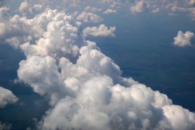 Aerial view from airplane window of white puffy clouds on bright sunny day.