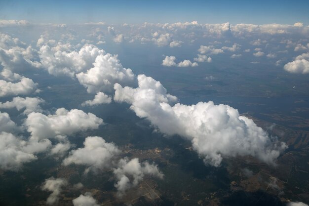 Aerial view from airplane window of white puffy clouds on bright sunny day.