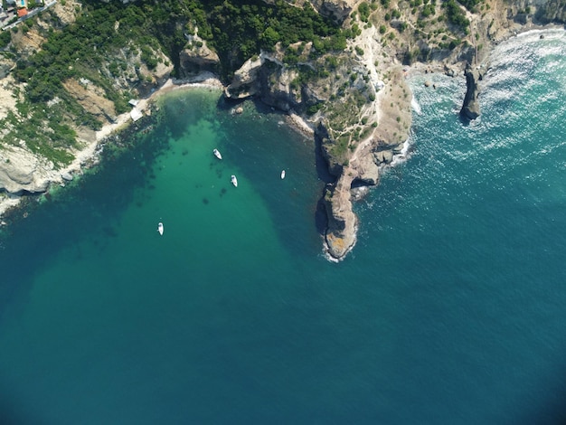 Aerial view from above on calm azure sea and volcanic rocky shores small waves on water surface in