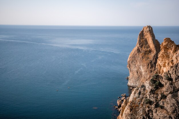 Aerial view from above on calm azure sea and volcanic rocky shores small waves on water surface in