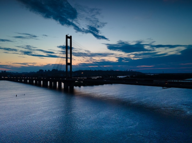 Photo aerial view from a drone on a cable-stayed bridge on a river in a big city in the evening