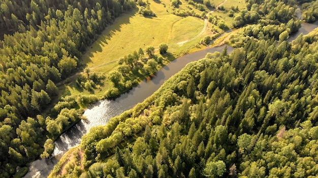 Aerial view from drone over curve river, meadow, forest and ground path.  Top nature landscape