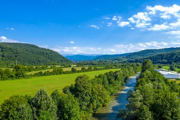 Aerial view from drone of the vast green landscape with river hills and blue sky
