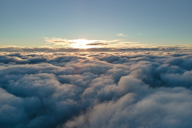 Aerial view from above at high altitude of dense puffy cumulus\
clouds flying in evening amazing sunset from airplane window point\
of view