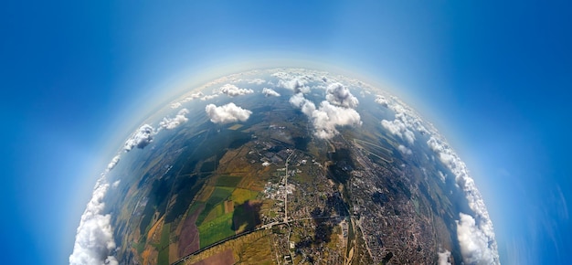 Aerial view from high altitude of little planet with distant\
city covered with puffy cumulus clouds flying by before rainstorm\
airplane point of view of landscape in cloudy weather