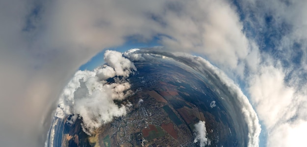 Foto vista aerea dall'alta quota del piccolo pianeta con la città lontana ricoperta di nubi cumuliformi gonfi che volano prima del temporale punto di vista dell'aereo del paesaggio con tempo nuvoloso