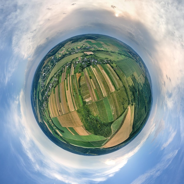 Фото Вид с воздуха с большой высоты на маленькую планету земля с зелеными и желтыми возделываемыми сельскохозяйственными полями с растущими культурами в яркий летний день