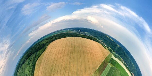 写真 明るい夏の日に熟した小麦と黄色の耕作農地と小さな惑星地球の高地からの空中写真