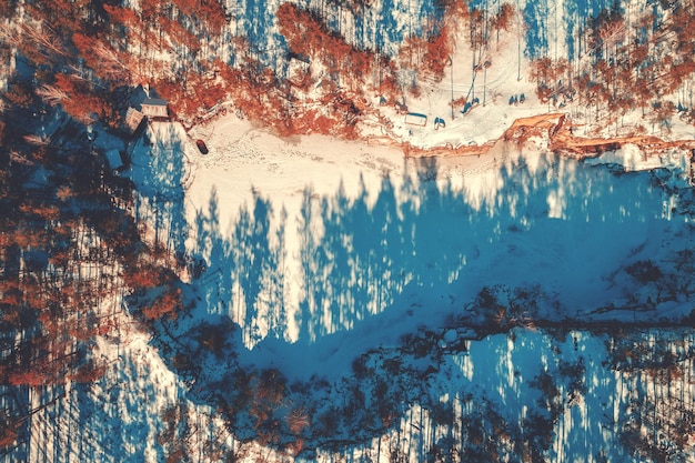 Aerial view of the frozen lake with a rocky shore. Granite quarry on a sunny day