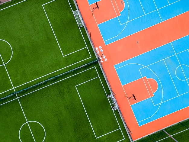 Aerial view of a green football field and a colorful basketball court providing a glimpse of two different sports facilities side by side