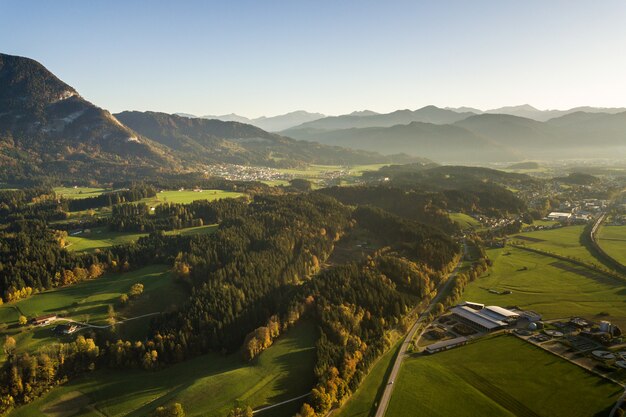 Photo aerial view of green meadows with villages and forest in austrian alps mountains.