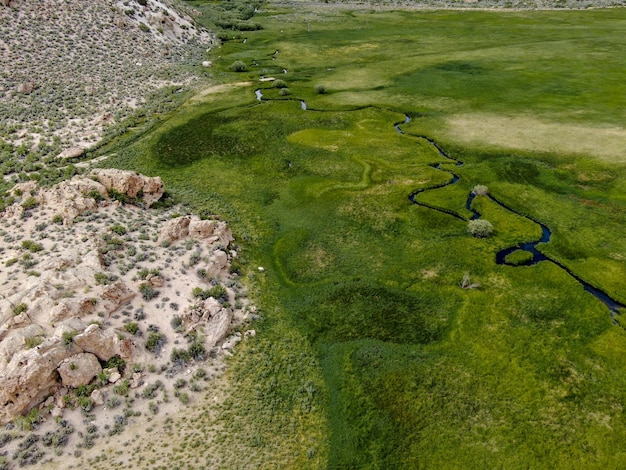 Aerial view of green valley with small curve river in Aspen Springs Mono County California USA