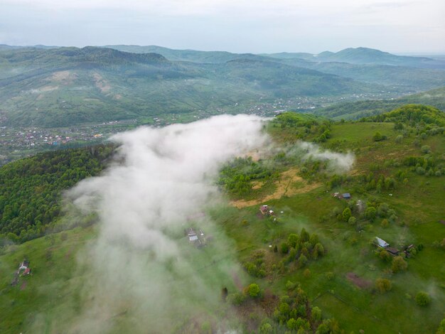 An aerial view of a green valley of Yaremche with a cloud cover trees seen from above