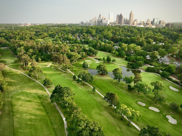 Aerial view of greenery field surrounded by dense trees in background of buildings in Atlanta