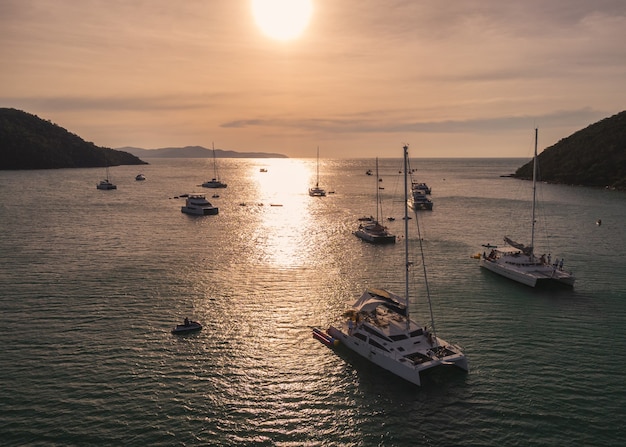 Aerial view of group of private yacht sailing on tropical sea at the sunset