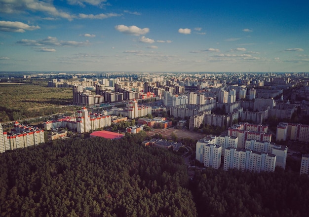 Aerial view of growing city in sunlight drone view of new\
building complex in city center with houses and roads under cloudy\
sky